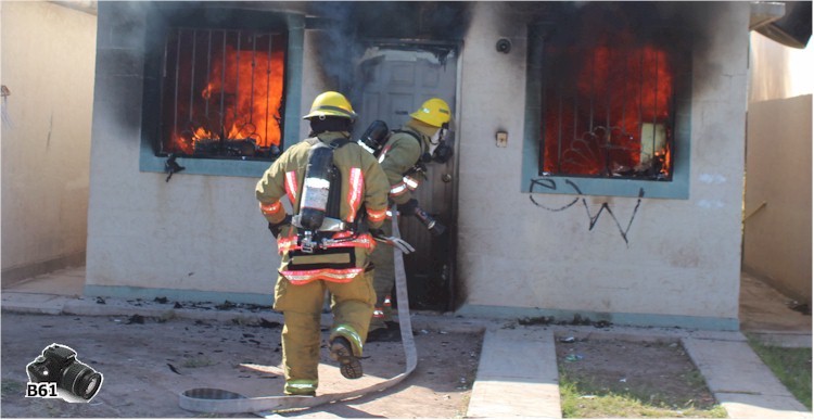 Bomberos ingresando a la vivienda completamente en llamas