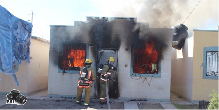 Bomberos ingresando a la vivienda completamente en llamas