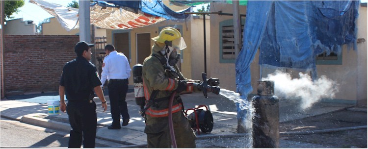 Bombero enfriando un cilindro que presenta fuga de gas LP