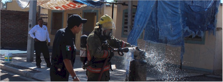 Bombero enfriando un cilindro que presenta fuga de gas LP